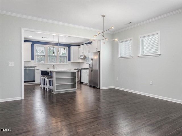 kitchen with a kitchen island, white cabinets, hanging light fixtures, and appliances with stainless steel finishes