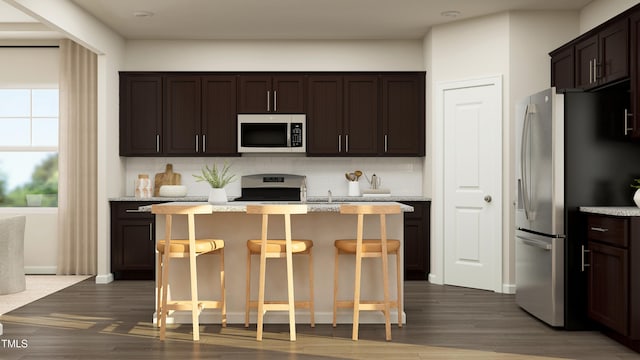 kitchen featuring a breakfast bar area, decorative backsplash, a center island, and dark hardwood / wood-style floors