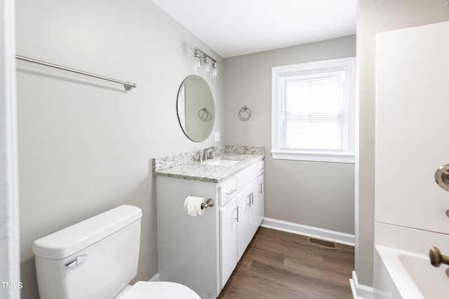 bathroom featuring a bathtub, vanity, wood-type flooring, and toilet