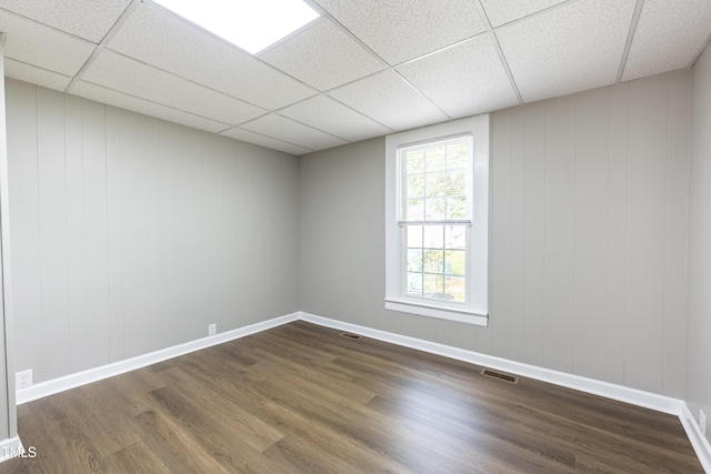 empty room featuring a drop ceiling and dark wood-type flooring