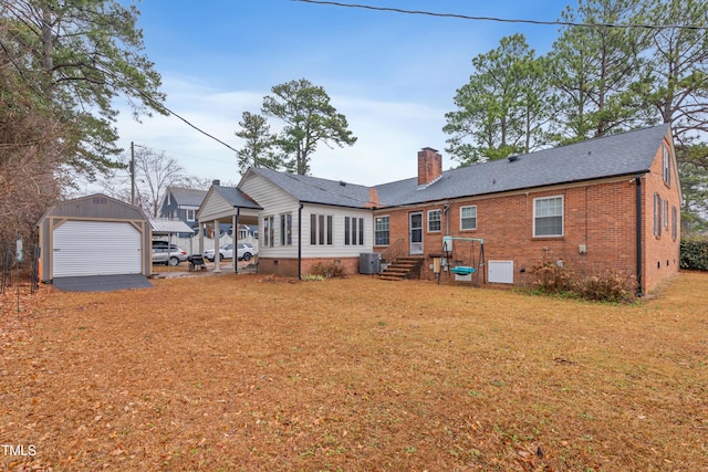 back of house with an outbuilding, a carport, a garage, and a lawn