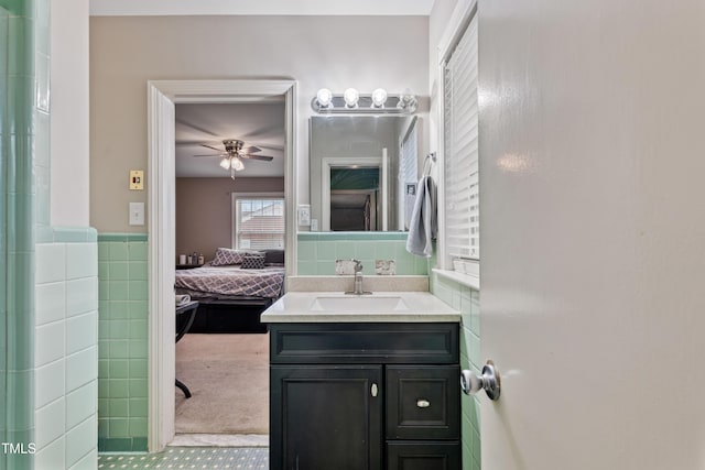 bathroom with ceiling fan, vanity, and tile walls