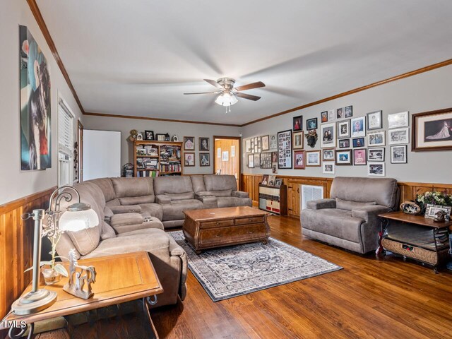 living room with crown molding, hardwood / wood-style flooring, ceiling fan, and wood walls