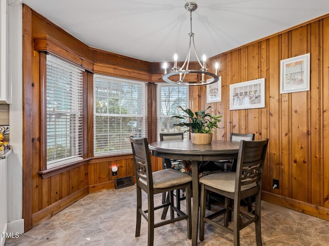 dining area featuring an inviting chandelier and wood walls