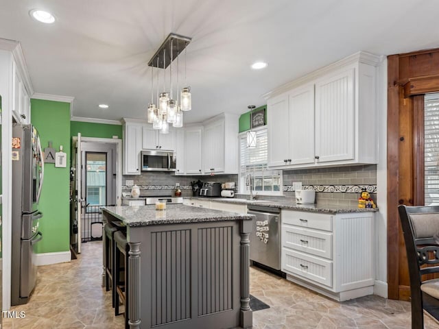 kitchen featuring appliances with stainless steel finishes, a breakfast bar, white cabinets, a center island, and light stone counters