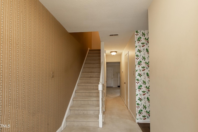 staircase with a textured ceiling