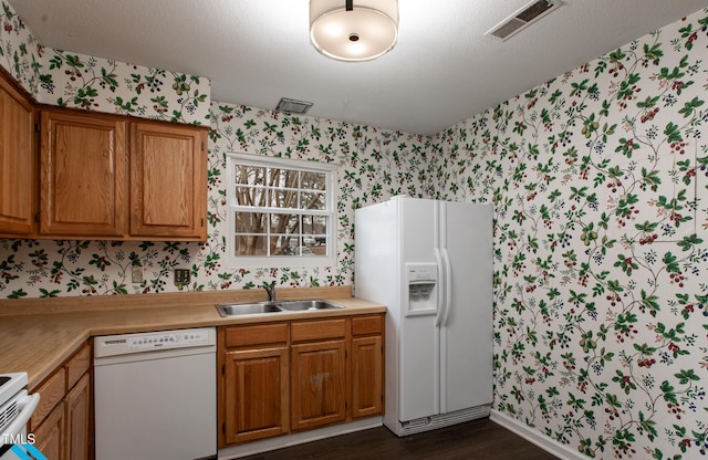 kitchen with a textured ceiling, white appliances, dark hardwood / wood-style floors, and sink