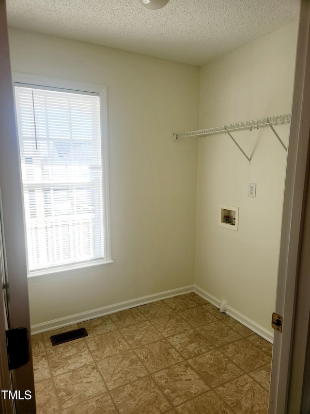 washroom with hookup for a washing machine and a textured ceiling