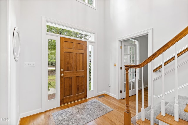 foyer with light wood-type flooring and a towering ceiling