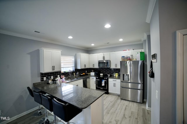 kitchen with kitchen peninsula, stainless steel appliances, white cabinets, and sink