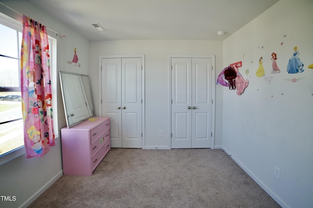 unfurnished bedroom with light colored carpet and two closets