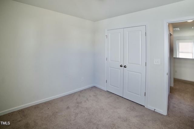 unfurnished bedroom with light colored carpet and a closet