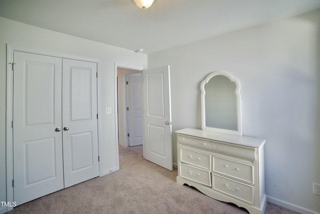 unfurnished bedroom with light colored carpet and a closet