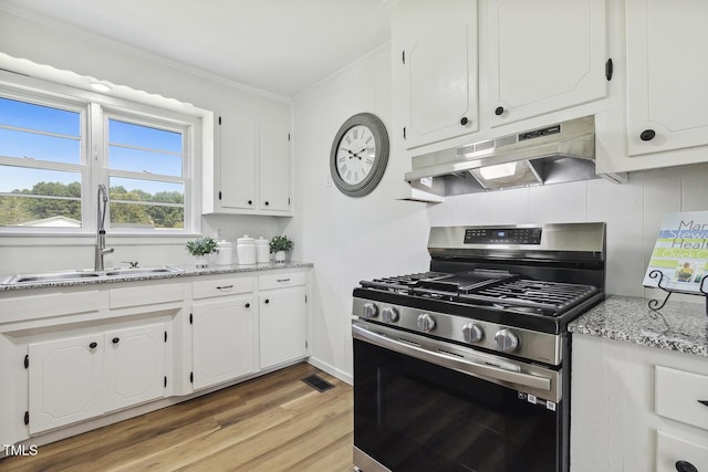 kitchen featuring sink, white cabinetry, light hardwood / wood-style floors, and stainless steel gas range oven