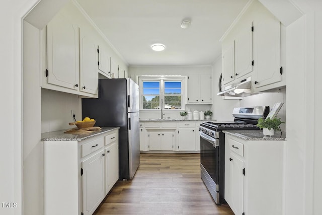 kitchen with sink, stainless steel appliances, white cabinets, and light hardwood / wood-style flooring