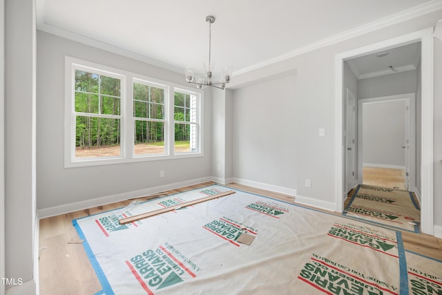 interior space featuring baseboards, wood finished floors, an inviting chandelier, and ornamental molding