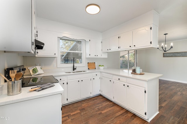 kitchen featuring kitchen peninsula, white cabinetry, sink, and pendant lighting