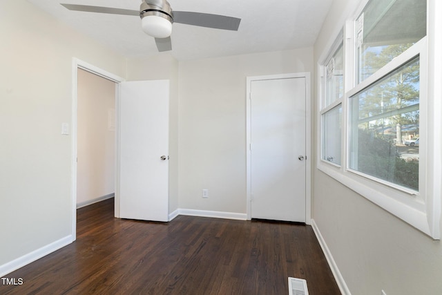 unfurnished bedroom featuring multiple windows, dark hardwood / wood-style flooring, a closet, and ceiling fan