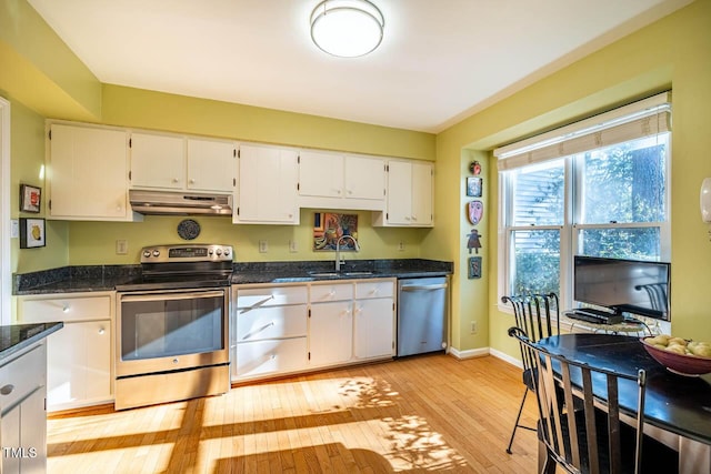 kitchen with dark stone countertops, stainless steel appliances, sink, light hardwood / wood-style flooring, and white cabinetry