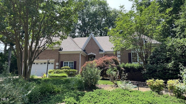 view of front of property with an attached garage, a shingled roof, and brick siding