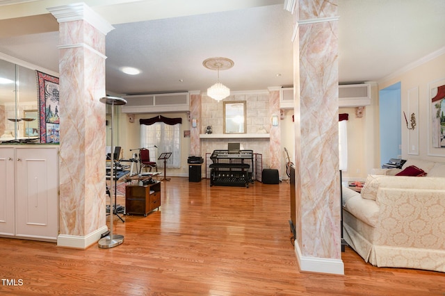 interior space featuring a wall mounted air conditioner, hardwood / wood-style floors, decorative columns, and crown molding