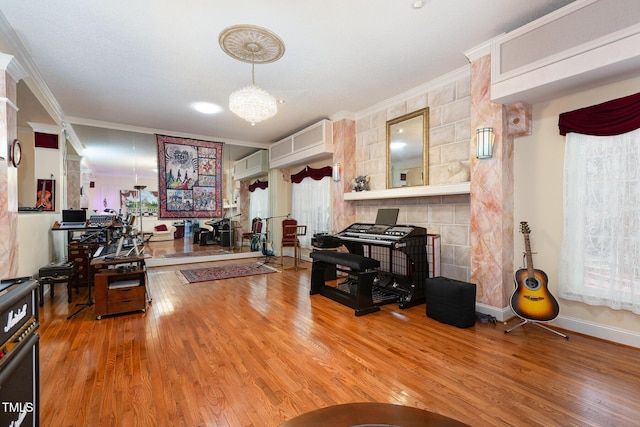 living room with a wall mounted AC, hardwood / wood-style flooring, an inviting chandelier, and crown molding