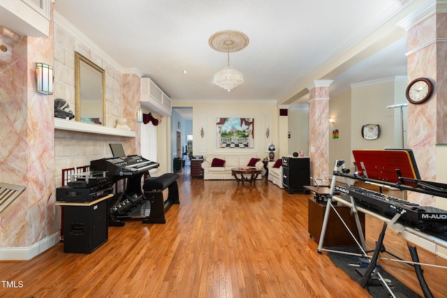 misc room with ornamental molding, light hardwood / wood-style flooring, an inviting chandelier, and decorative columns