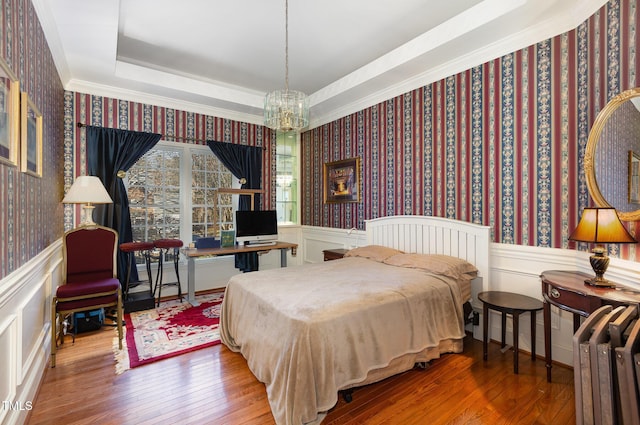 bedroom with a tray ceiling, crown molding, a chandelier, and wood-type flooring