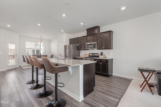 kitchen featuring a breakfast bar, stainless steel appliances, sink, a center island with sink, and a chandelier