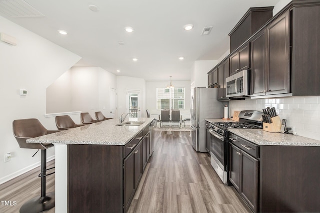 kitchen featuring hardwood / wood-style floors, a kitchen breakfast bar, sink, and appliances with stainless steel finishes