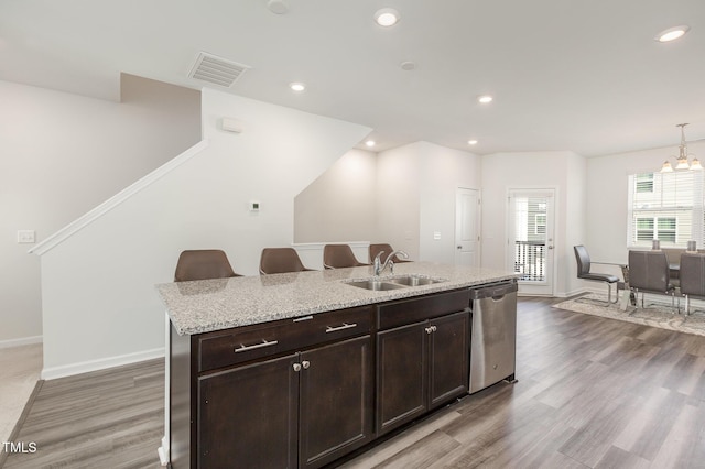 kitchen with dark brown cabinetry, sink, wood-type flooring, a center island with sink, and dishwasher