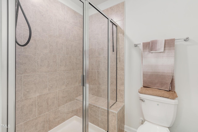 bathroom featuring toilet and a shower with door