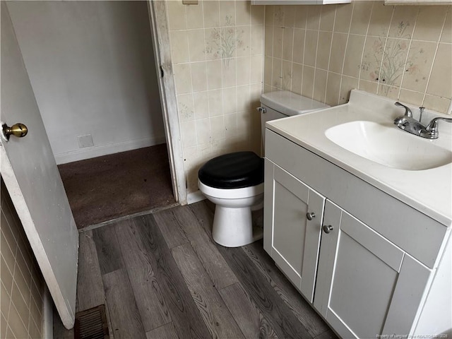 bathroom featuring wood-type flooring, vanity, toilet, and tile walls