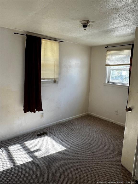 carpeted spare room featuring a textured ceiling