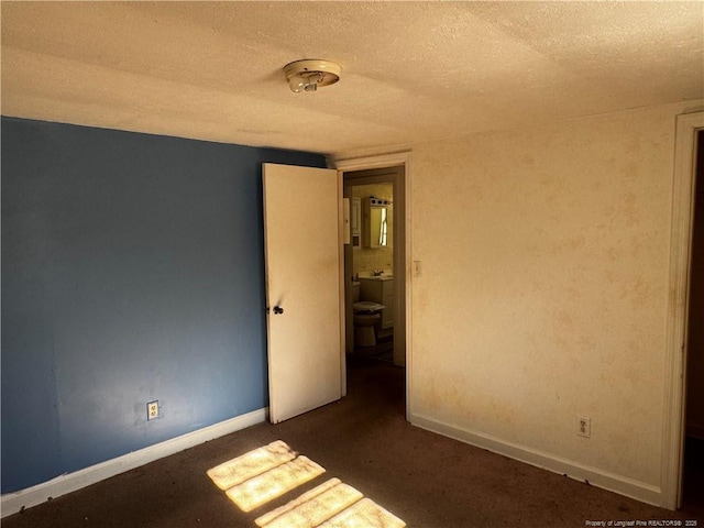 spare room with a textured ceiling and dark colored carpet