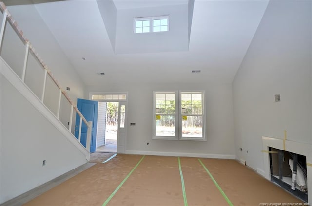 unfurnished living room featuring a towering ceiling and a fireplace