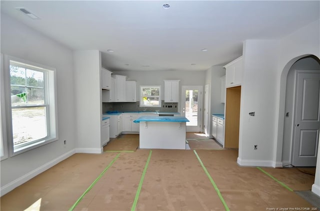 kitchen with white cabinetry, a kitchen island, and tasteful backsplash