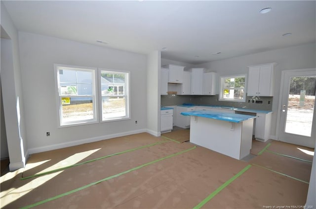 kitchen with a kitchen bar, a center island, tasteful backsplash, and white cabinetry