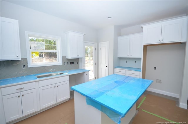 kitchen featuring a center island, backsplash, sink, a kitchen bar, and white cabinetry