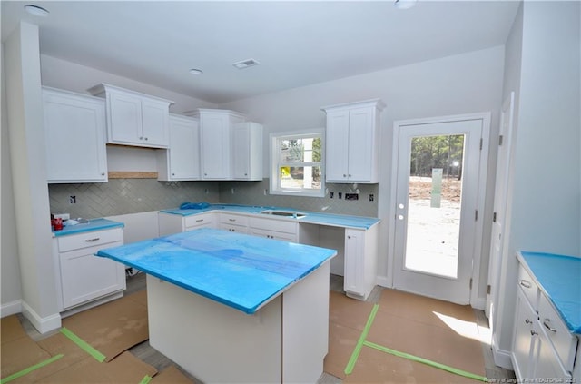 kitchen with decorative backsplash, white cabinetry, and a kitchen island