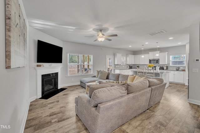 living room featuring ceiling fan and light hardwood / wood-style floors