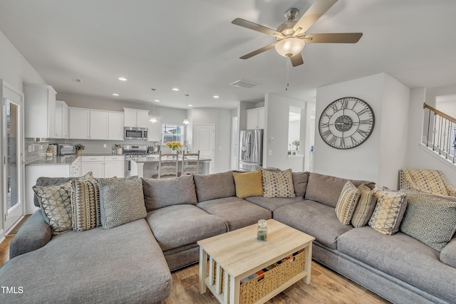 living room featuring light hardwood / wood-style flooring and ceiling fan