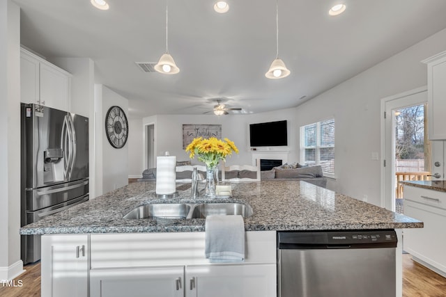 kitchen with a kitchen island with sink, white cabinets, and appliances with stainless steel finishes