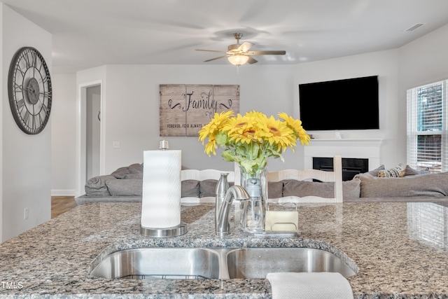 interior space with ceiling fan, light stone countertops, and sink