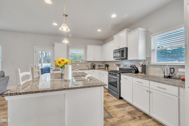 kitchen with white cabinets, appliances with stainless steel finishes, and a center island with sink