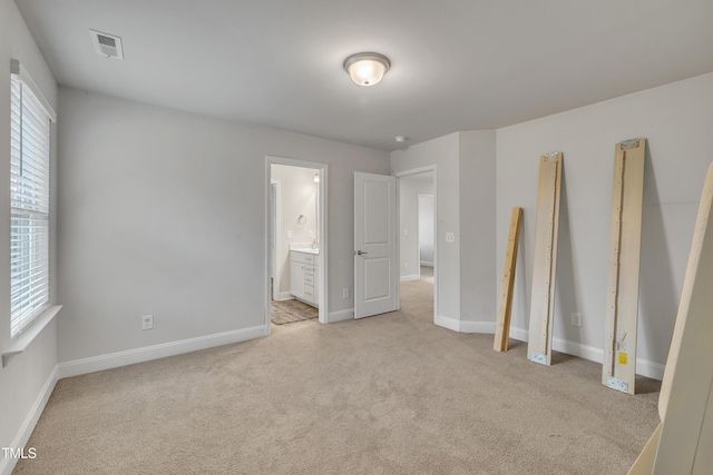 unfurnished bedroom featuring ensuite bathroom and light colored carpet