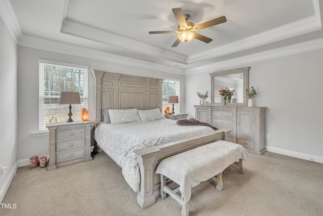 carpeted bedroom with a tray ceiling, multiple windows, ceiling fan, and ornamental molding