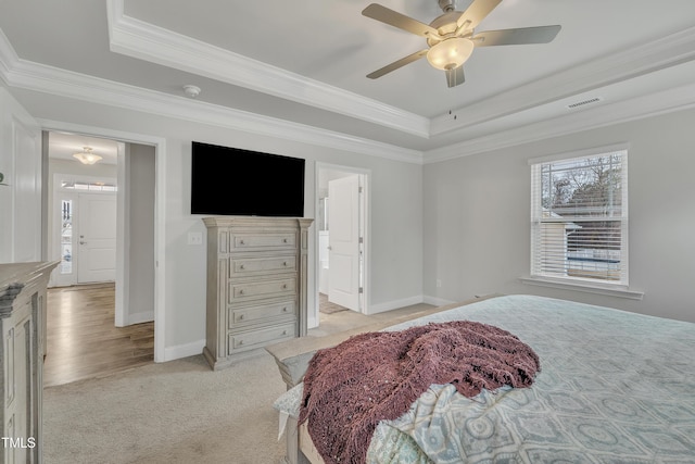 carpeted bedroom with ceiling fan, a raised ceiling, and ornamental molding