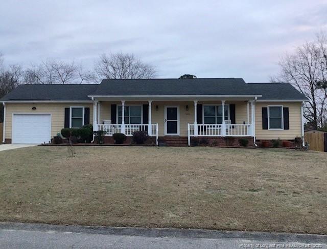 ranch-style house featuring a porch, a garage, and a front lawn