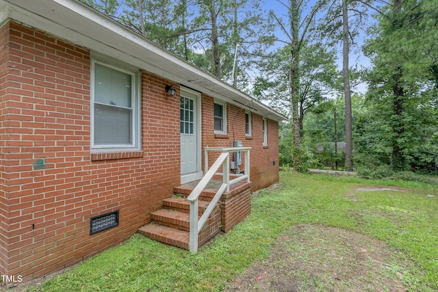 view of exterior entry featuring a lawn